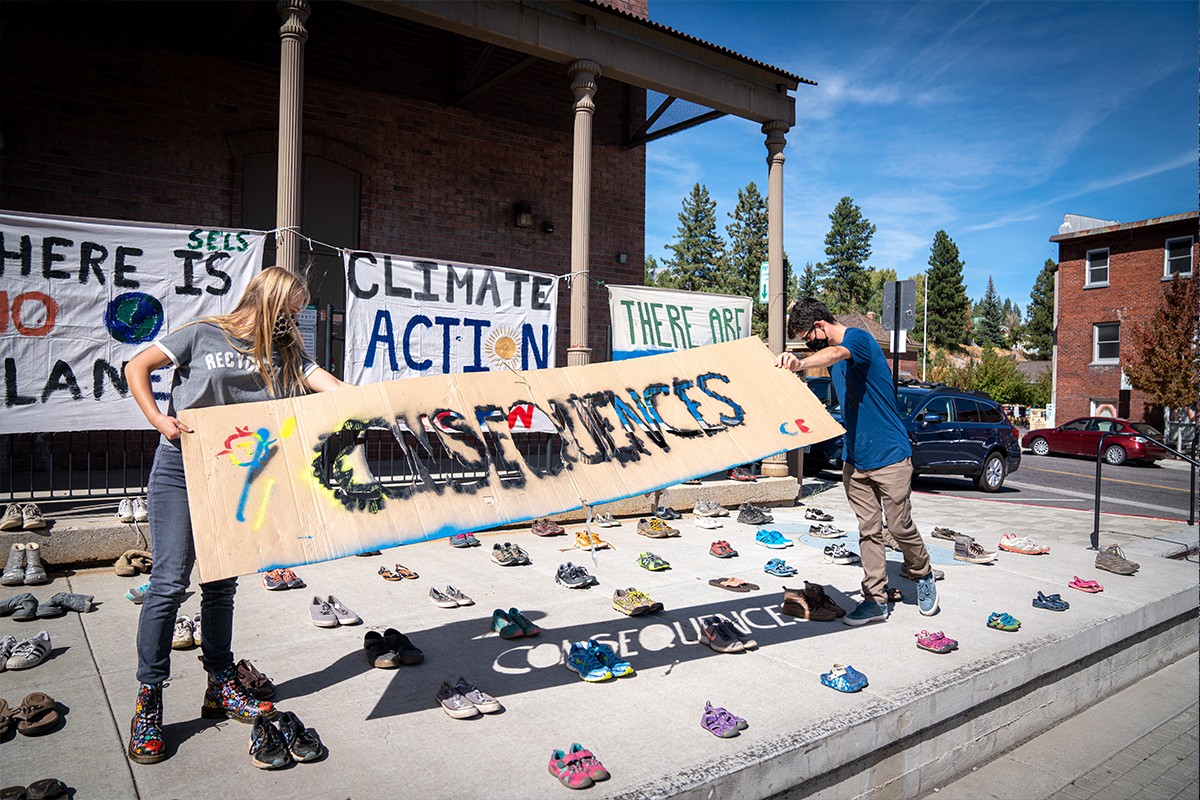 Two students holding a sign that says 'Consequences'